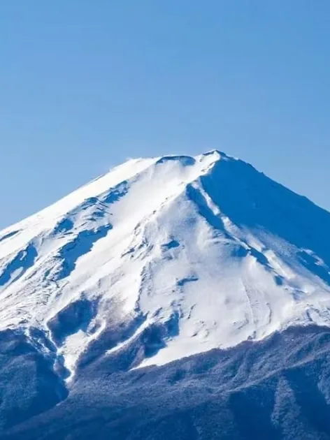Der schneebedeckte Gipfelkegel des Fuji vor tiefblauem Himmel