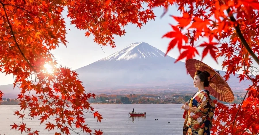 Rote Ahornblätter rahmen den Fuji über einem See ein, rechts eine Frau im Kimono mit rotem Schirm