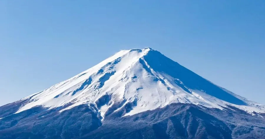 Der schneebedeckte Gipfelkegel des Fuji vor tiefblauem Himmel
